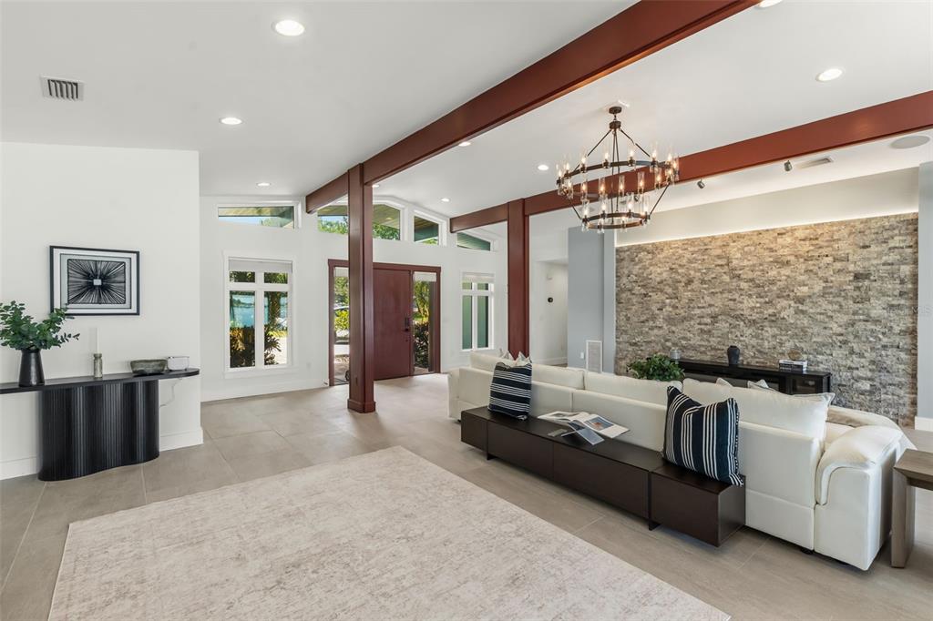 A living room features a stone accent wall, exposed wooden beams, and a white sofa — 4598 CLEARWATER HARBOR DRIVE S, LARGO, FL
