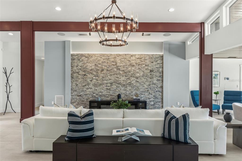 A living room features a stone accent wall, a large white sofa, and a chandelier — 4598 CLEARWATER HARBOR DRIVE S, LARGO, FL