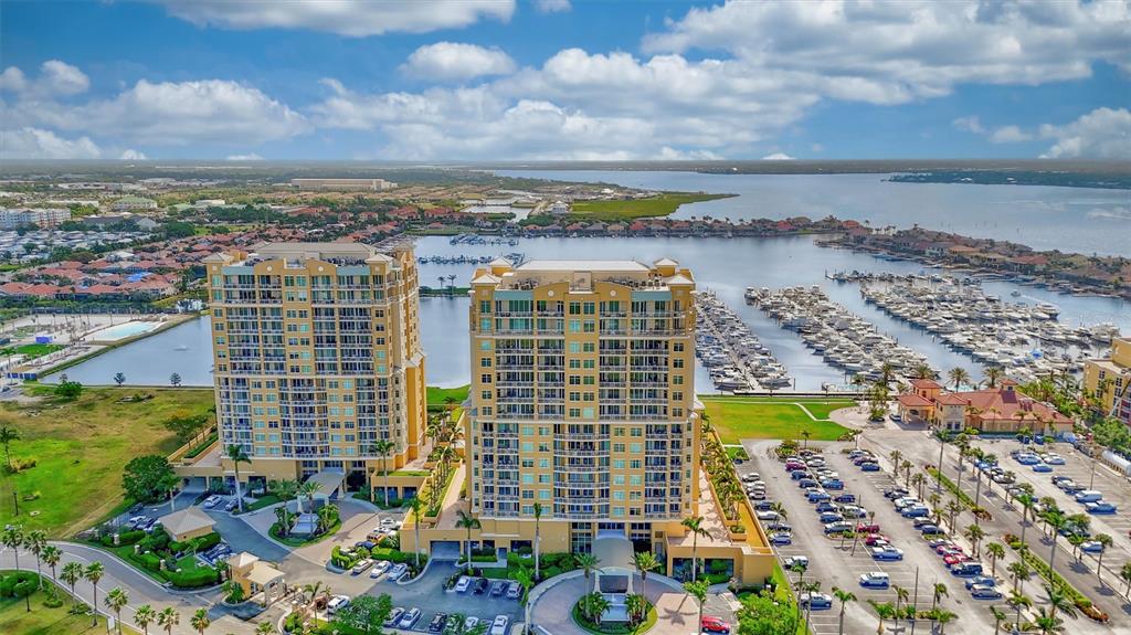An aerial view shows two tall residential buildings next to a marina and parking lot — 130 RIVIERA DUNES WAY UNIT PH202, PALMETTO, FL