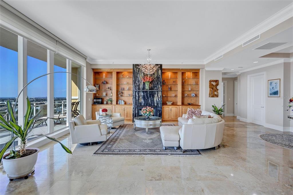 A living room features a marble fireplace, built-in wooden shelving, and floor-to-ceiling windows — 130 RIVIERA DUNES WAY UNIT PH202, PALMETTO, FL