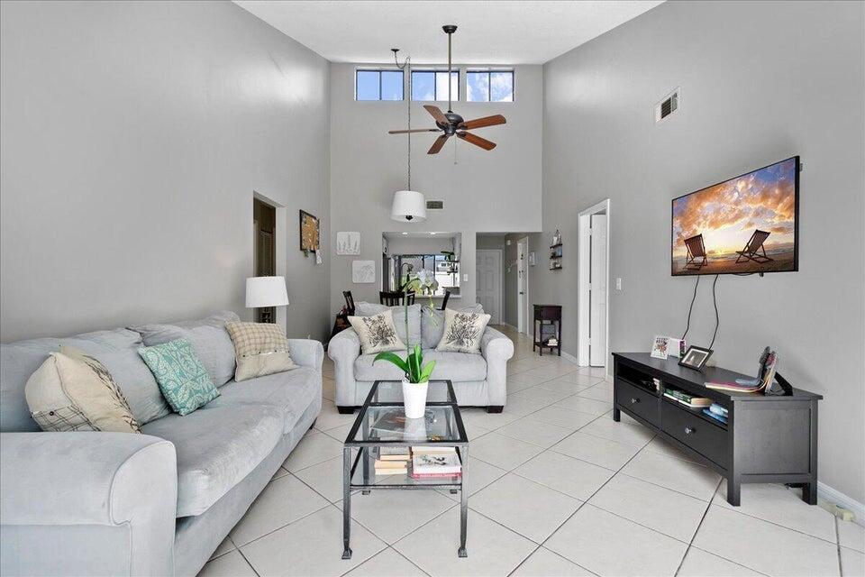 A living room features light gray walls, tile flooring, a vaulted ceiling, and a ceiling fan — 12875 Spinnaker Lane, Wellington FL 33414, WELLINGTON, FL