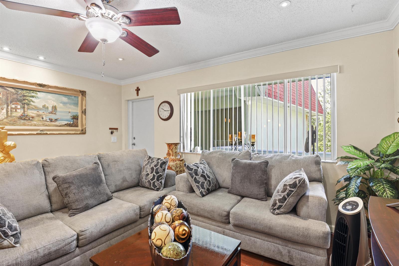 A living room features a gray sectional sofa, a ceiling fan, and a large window — 3100 Springdale Boulevard # 308, Palm Springs FL 33461, PALM SPRINGS, FL