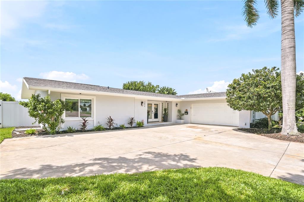 A single-story house with a white exterior, a large concrete driveway, and a palm tree — 3896 42ND AVENUE S, ST PETERSBURG, FL