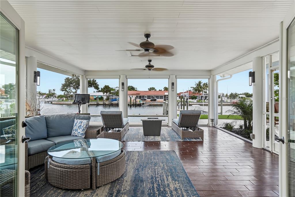 A covered patio features wicker furniture, a pool, and a view of the waterfront — 3896 42ND AVENUE S, ST PETERSBURG, FL
