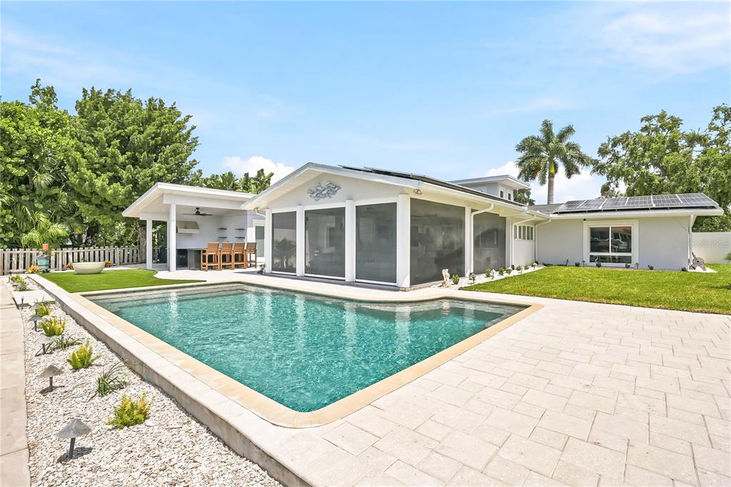 A backyard features a swimming pool, a covered patio with seating, and an outdoor kitchen — 3896 42ND AVENUE S, ST PETERSBURG, FL