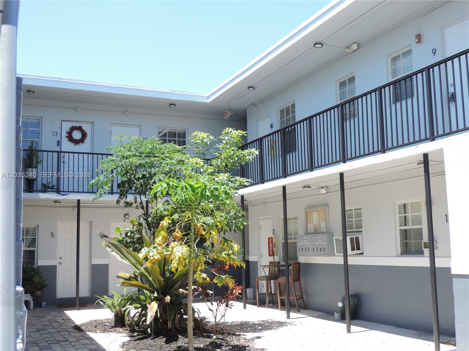 An exterior view of a two-story apartment complex courtyard with a central garden area — 3615 Thomas Ave # 11, Miami FL 33133, MIAMI, FL