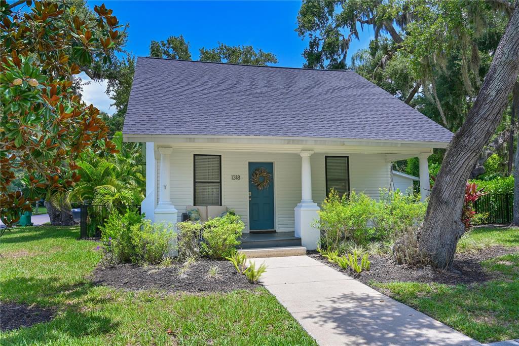 A white cottage with a teal front door and a dark shingled roof — 1318 6TH STREET W, PALMETTO, FL
