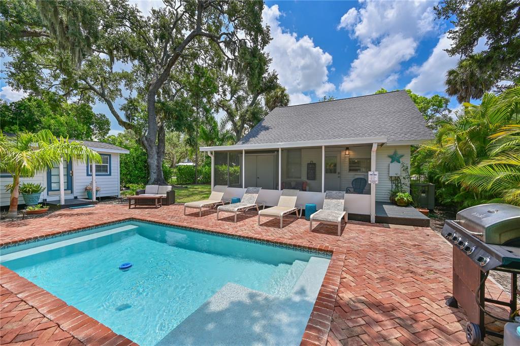 A backyard features a rectangular swimming pool, brick patio, lounge chairs, and a screened porch — 1318 6TH STREET W, PALMETTO, FL