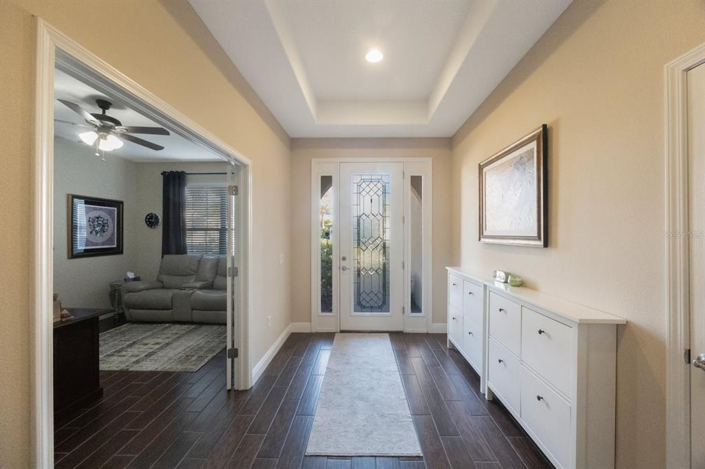 A foyer with dark wood floors, a tray ceiling, and a white shoe cabinet — 2564 GRAND CYPRESS BOULEVARD, PALM HARBOR, FL