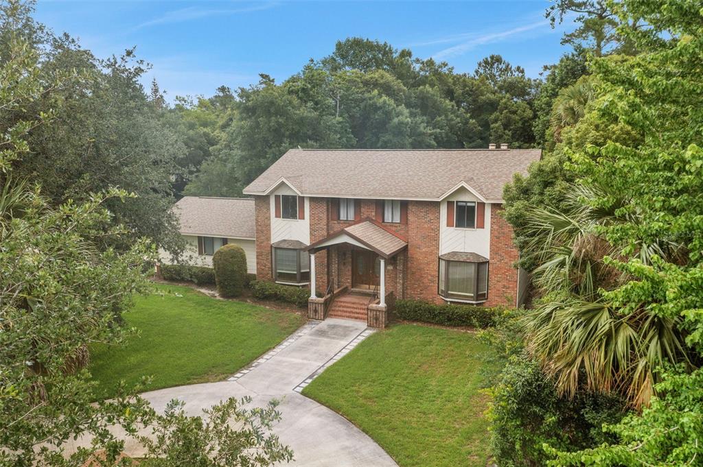 A two-story brick house with a gabled roof and a concrete walkway in a yard — 230 HUNTERS TRAIL, LONGWOOD, FL