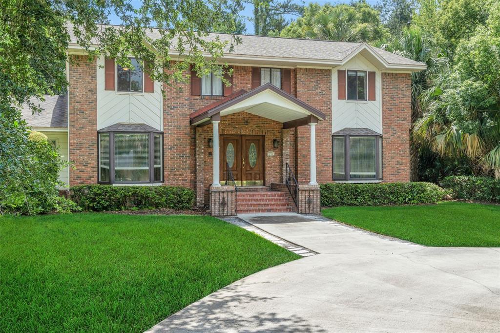 A two-story brick house with a covered front porch, bay windows, and a concrete driveway — 230 HUNTERS TRAIL, LONGWOOD, FL