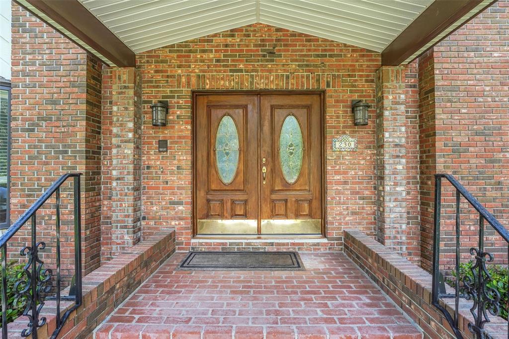 A brick entryway features a double wooden door with oval glass inserts under a porch — 230 HUNTERS TRAIL, LONGWOOD, FL
