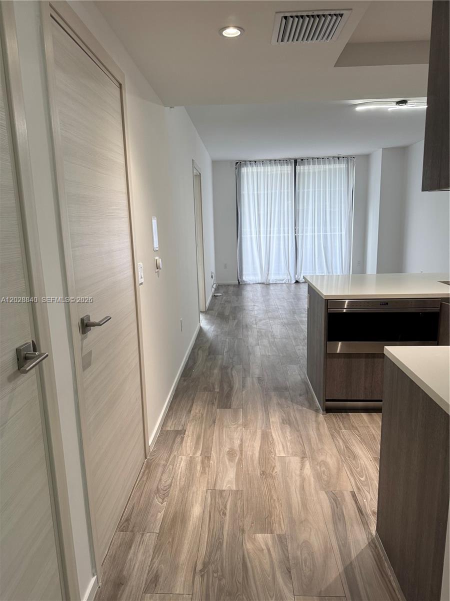 A hallway leads from a kitchen with dark cabinetry toward a room with floor-to-ceiling curtains — 801 S Miami Ave # 1808, Miami FL 33130, MIAMI, FL