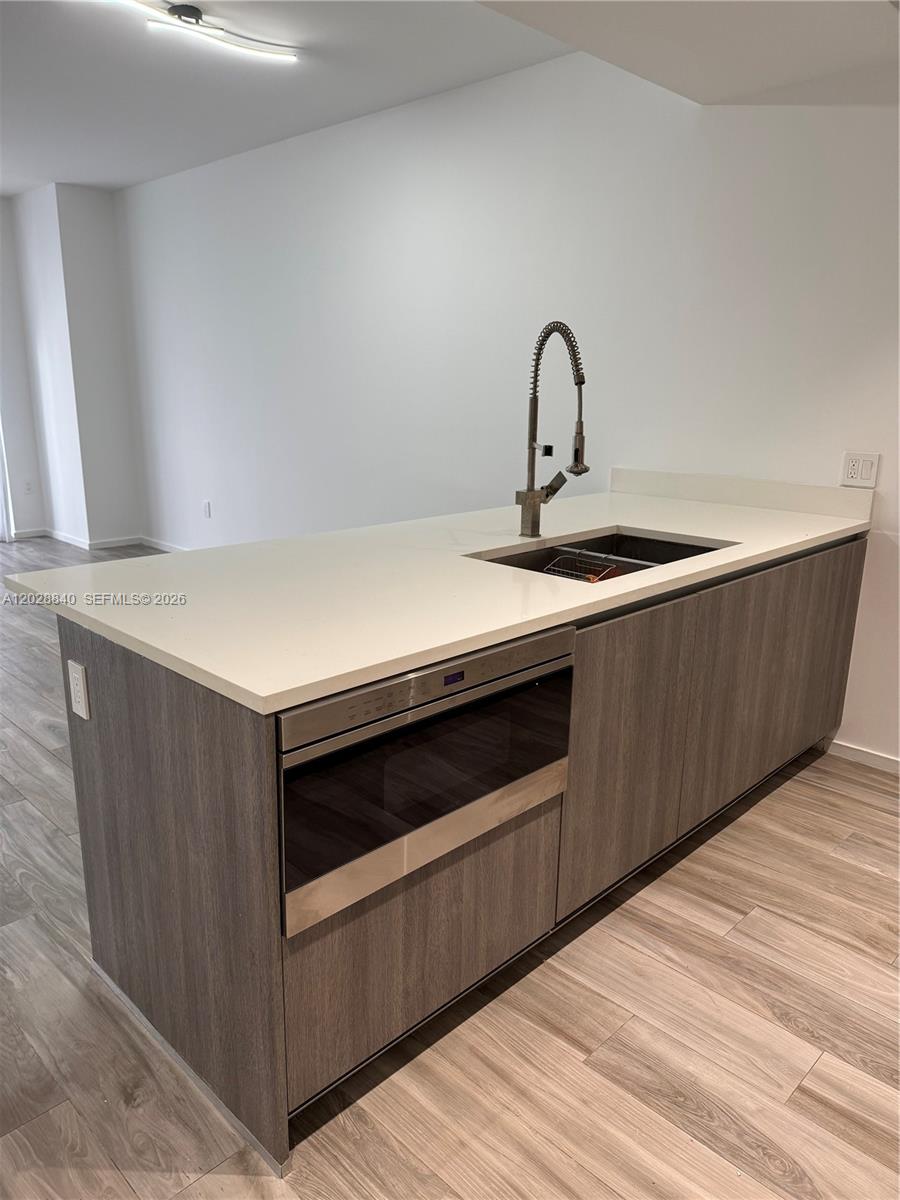 A kitchen island features a stainless steel microwave drawer, a sink, and wood-grain cabinetry — 801 S Miami Ave # 1808, Miami FL 33130, MIAMI, FL