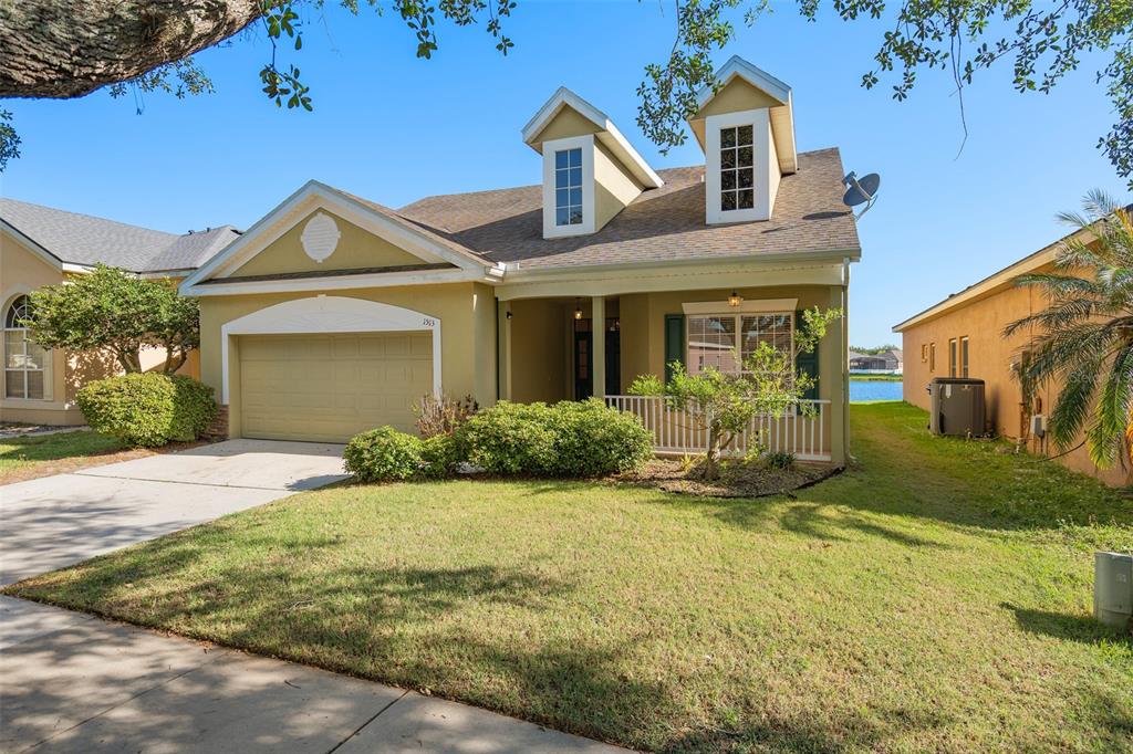 A two-story house with a tan exterior, a two-car garage, and two roof dormers — 1513 HARRIER DRIVE, ORLANDO, FL