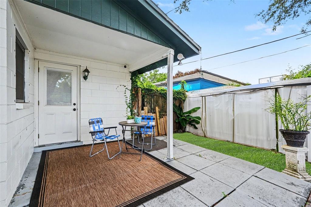 A patio with a brown rug, two chairs, a small table, and a grassy area — 8115 N OLA AVENUE, TAMPA, FL