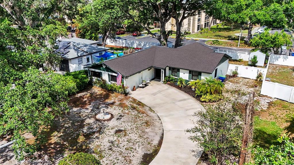 An aerial view shows a single-story house with a dark roof and a curved driveway — 8115 N OLA AVENUE, TAMPA, FL