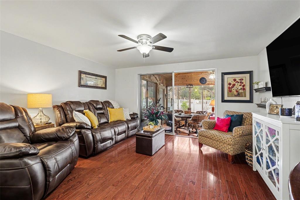 A living room features brown leather furniture, a patterned armchair, and sliding glass patio doors — 8115 N OLA AVENUE, TAMPA, FL
