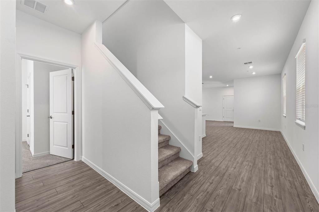 An interior view shows a staircase with carpeted steps, wood-look flooring, and white walls — 4692 INNER WORLD LANE, WESLEY CHAPEL, FL