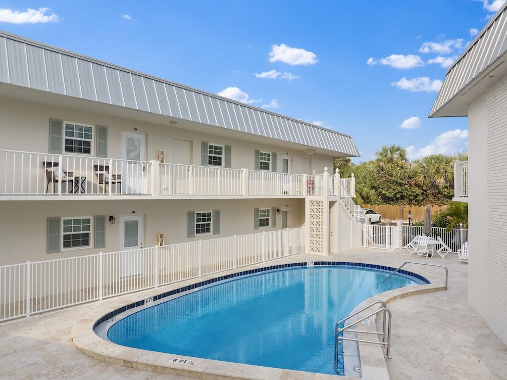 A two-story motel building with a swimming pool and white metal railings in the foreground — 900 Jasmine Lane # 10a, Vero Beach FL 32963, VERO BEACH, FL