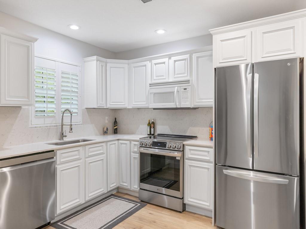A kitchen featuring white cabinets, stainless steel appliances, and light-colored countertops — 900 Jasmine Lane # 10a, Vero Beach FL 32963, VERO BEACH, FL