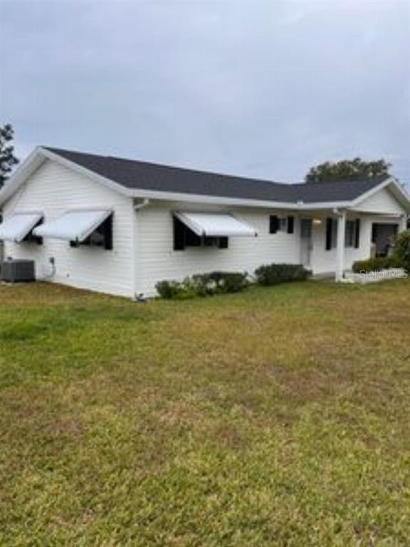 A white single-story house with a dark roof and metal window awnings sits on grass — 17624 SE 108TH TERRACE, SUMMERFIELD, FL