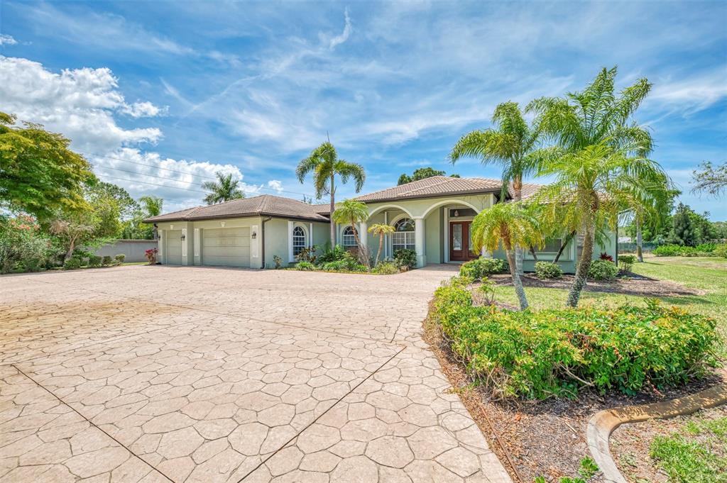 A single-story house with a large stamped concrete driveway and palm trees in the front — 900 PARK PLACE DRIVE, ENGLEWOOD, FL