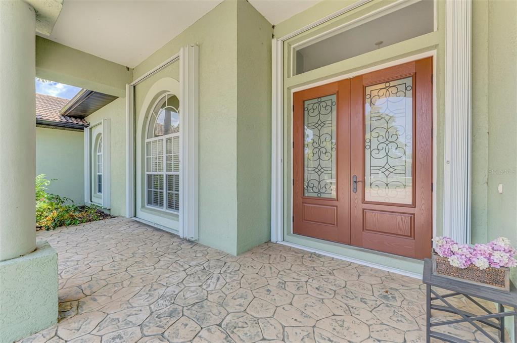 A covered entryway features a stone-patterned floor, light green walls, and double wood front doors — 900 PARK PLACE DRIVE, ENGLEWOOD, FL