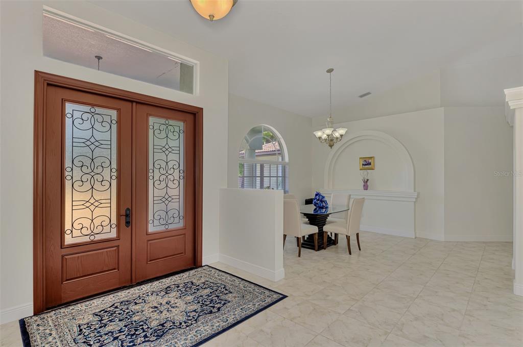 An entryway with a double wooden door, tiled floors, and an adjacent dining area — 900 PARK PLACE DRIVE, ENGLEWOOD, FL