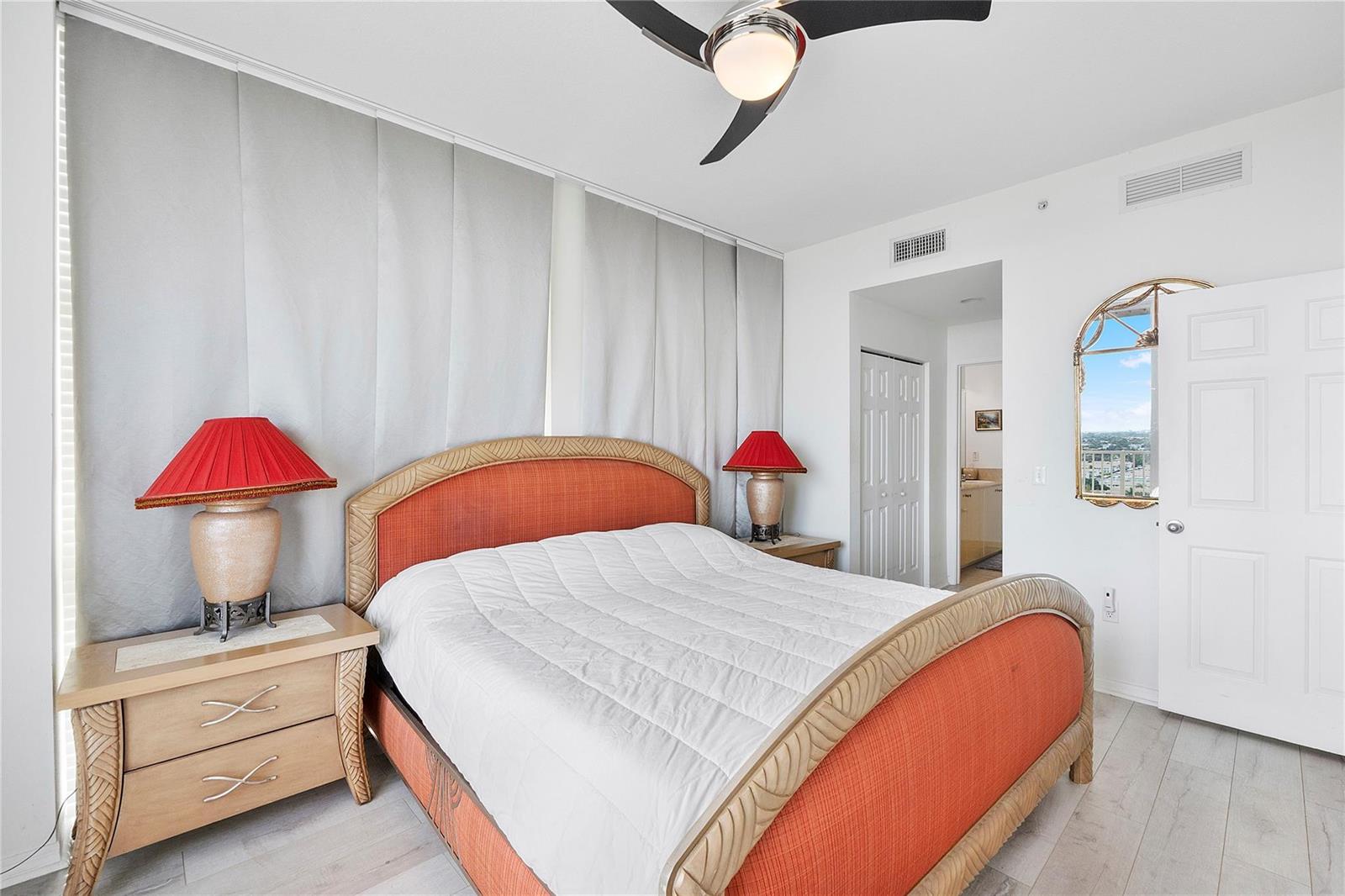 A bedroom features a bed with an orange headboard, two lamps, and a ceiling fan — 625 Casa Loma Boulevard # 1608, Boynton Beach FL 33435, BOYNTON BEACH, FL