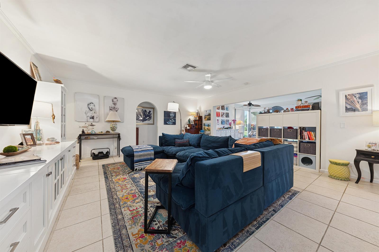 A living room features a large blue sectional sofa, a colorful area rug, and white cabinetry — 13 Fairway, Boynton Beach FL 33436, BOYNTON BEACH, FL