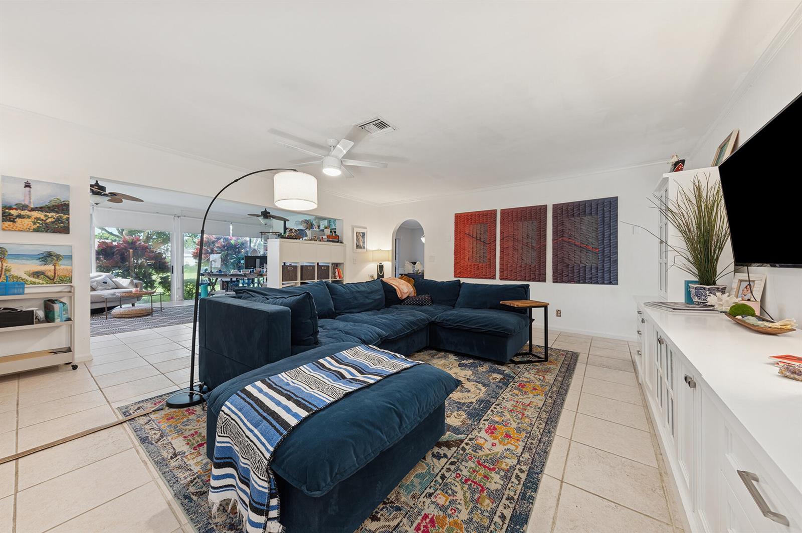 A living room features a blue sectional sofa, a patterned area rug, and white cabinetry — 13 Fairway, Boynton Beach FL 33436, BOYNTON BEACH, FL