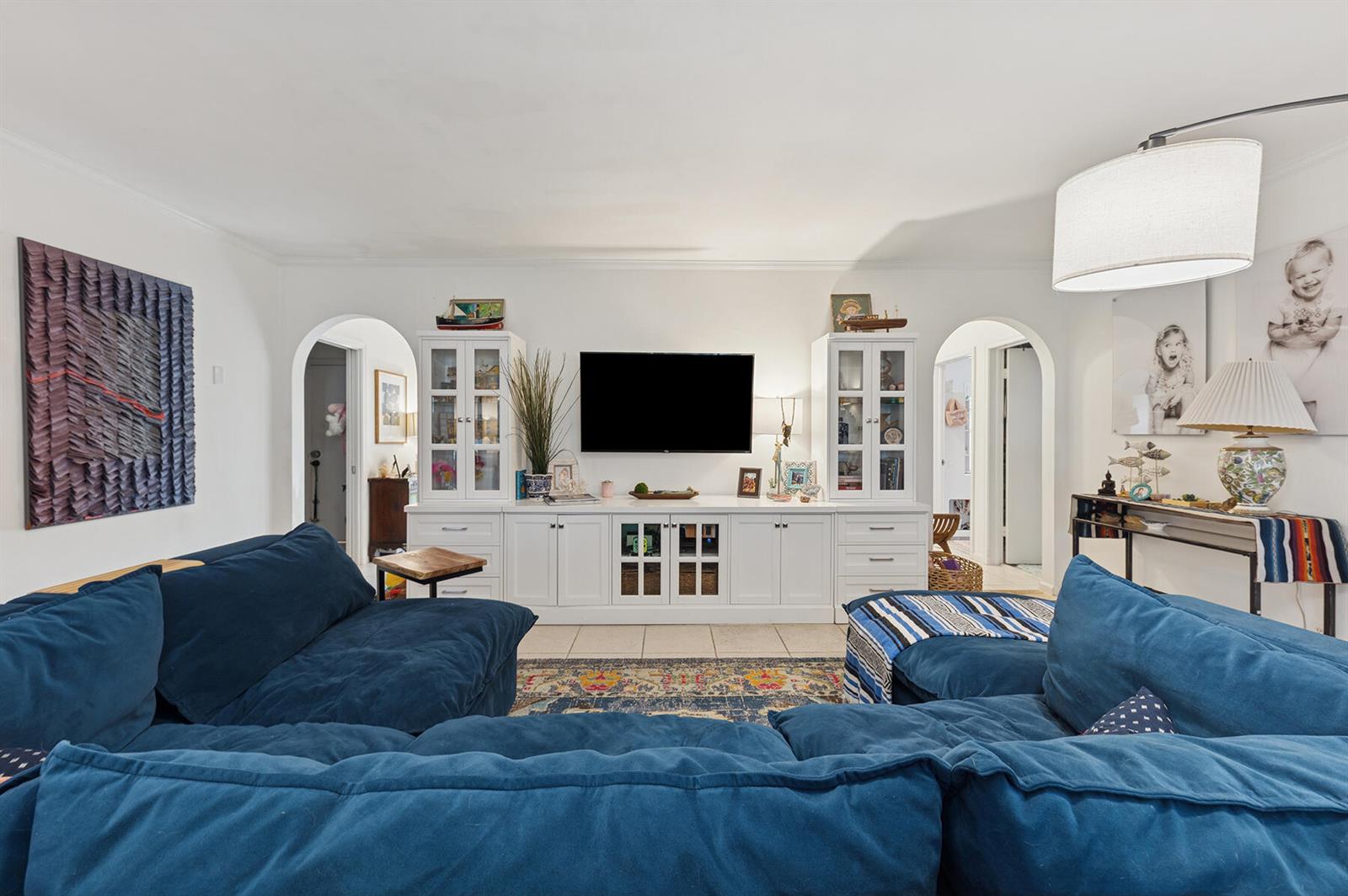 A living room features a blue sectional sofa, white built-in cabinetry, and two arched doorways — 13 Fairway, Boynton Beach FL 33436, BOYNTON BEACH, FL