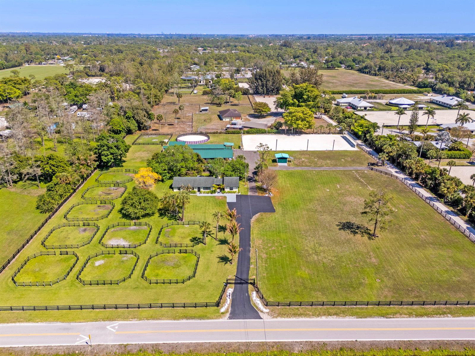 An aerial view shows a rural property with a house, multiple fenced paddocks, and arenas — 1230 F Road, FL 33470, FL