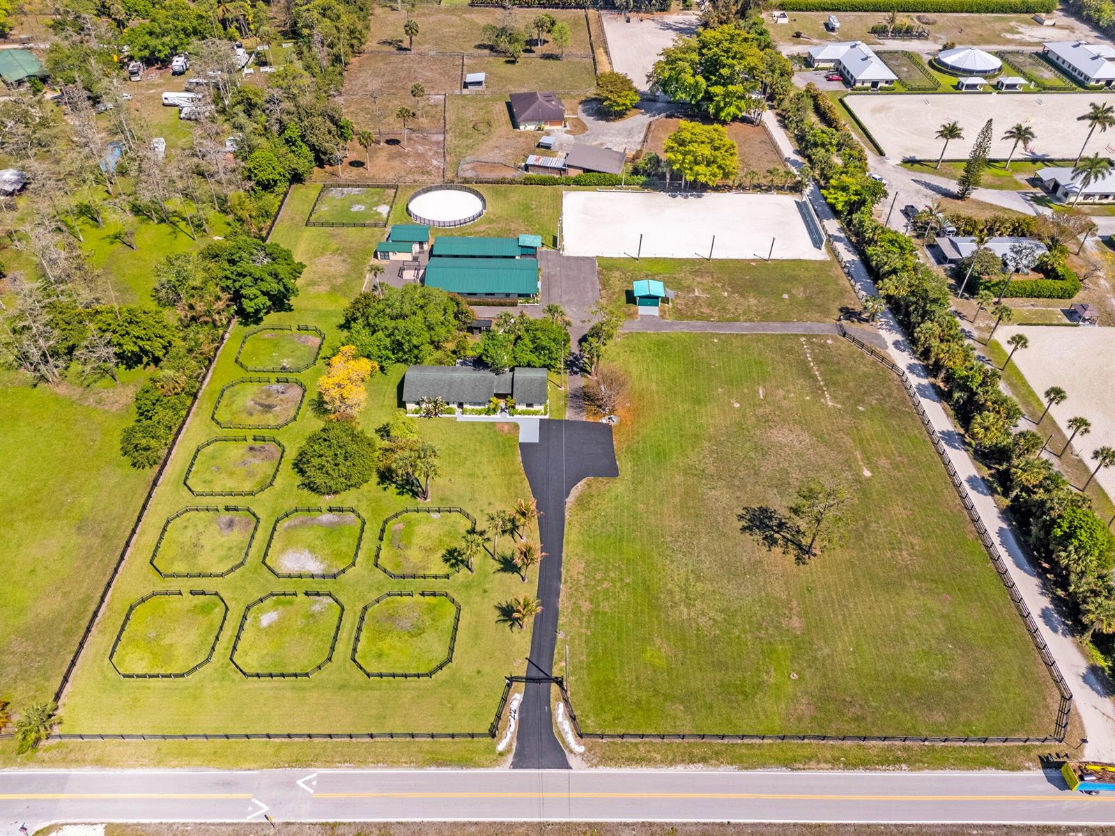 An aerial view shows a residential property with a house, stables, and fenced paddocks — 1230 F Road, FL 33470, FL