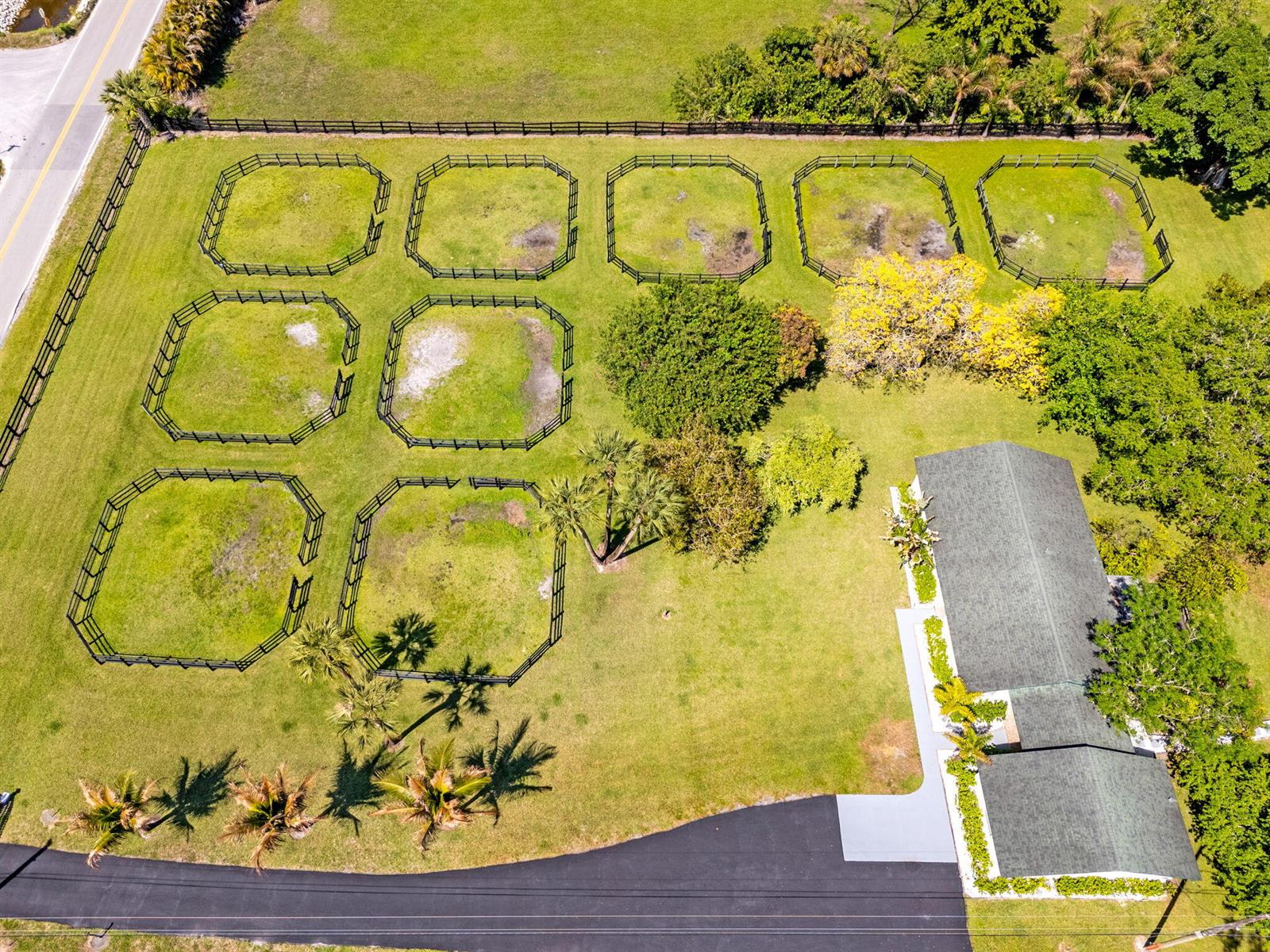 An aerial view shows a house with a driveway and eight fenced-in grass paddocks — 1230 F Road, FL 33470, FL