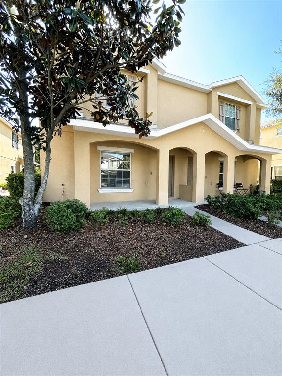 A two-story tan stucco house features a covered front porch and a large magnolia tree — 4714 CHATTERTON WAY, RIVERVIEW, FL