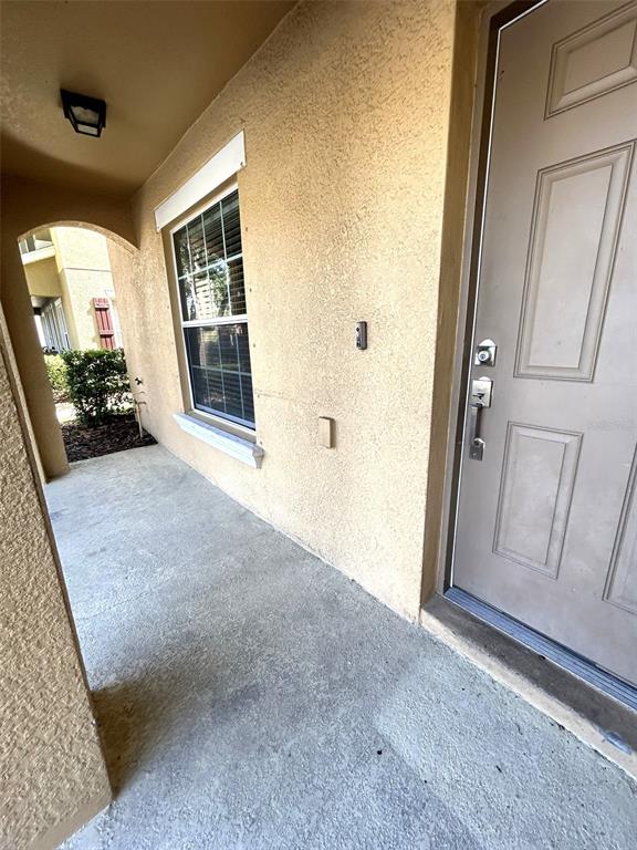 A beige stucco exterior wall features a window, a front door, and a porch light — 4714 CHATTERTON WAY, RIVERVIEW, FL