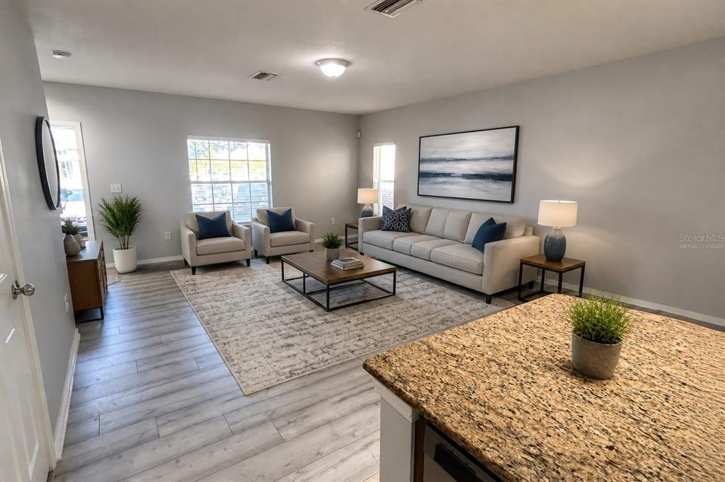 A living room with light gray walls, wood-look flooring, a sofa, two armchairs, and a rug — 4714 CHATTERTON WAY, RIVERVIEW, FL