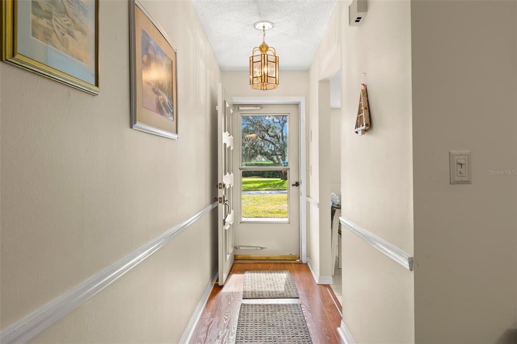An entryway features hardwood floors, a light fixture, and a door opening to a yard — 1084 DUNROBIN DRIVE UNIT D, PALM HARBOR, FL