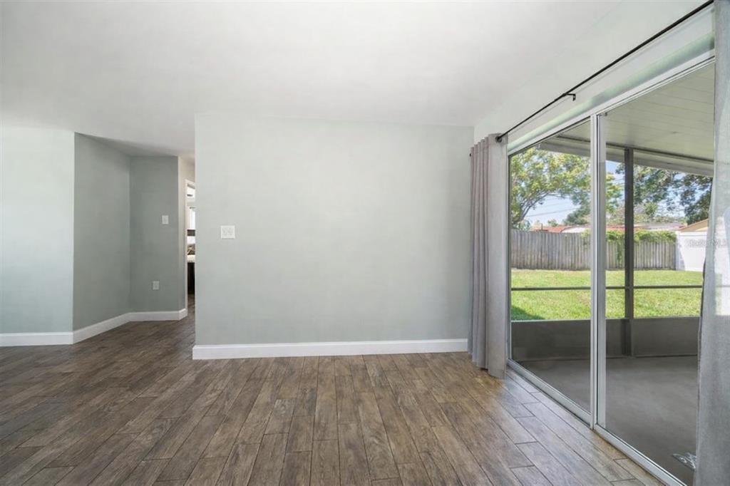 An empty room with wood-look tile flooring and a sliding glass door leading to a patio — 2132 ISABELLE STREET, LARGO, FL