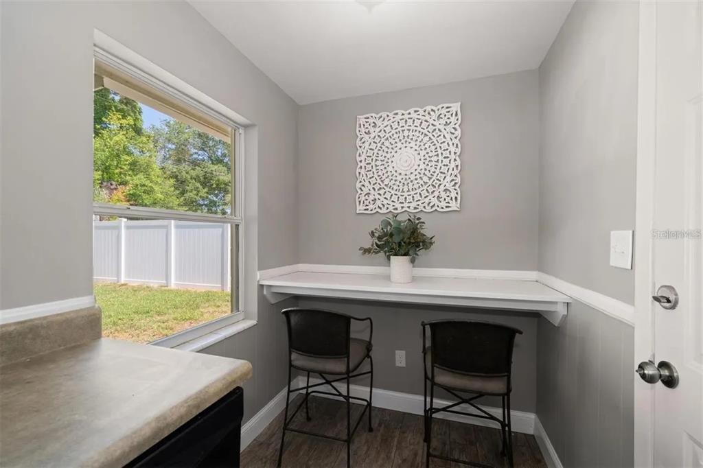 A small breakfast nook features a white wall-mounted desk, two stools, and a large window — 2132 ISABELLE STREET, LARGO, FL