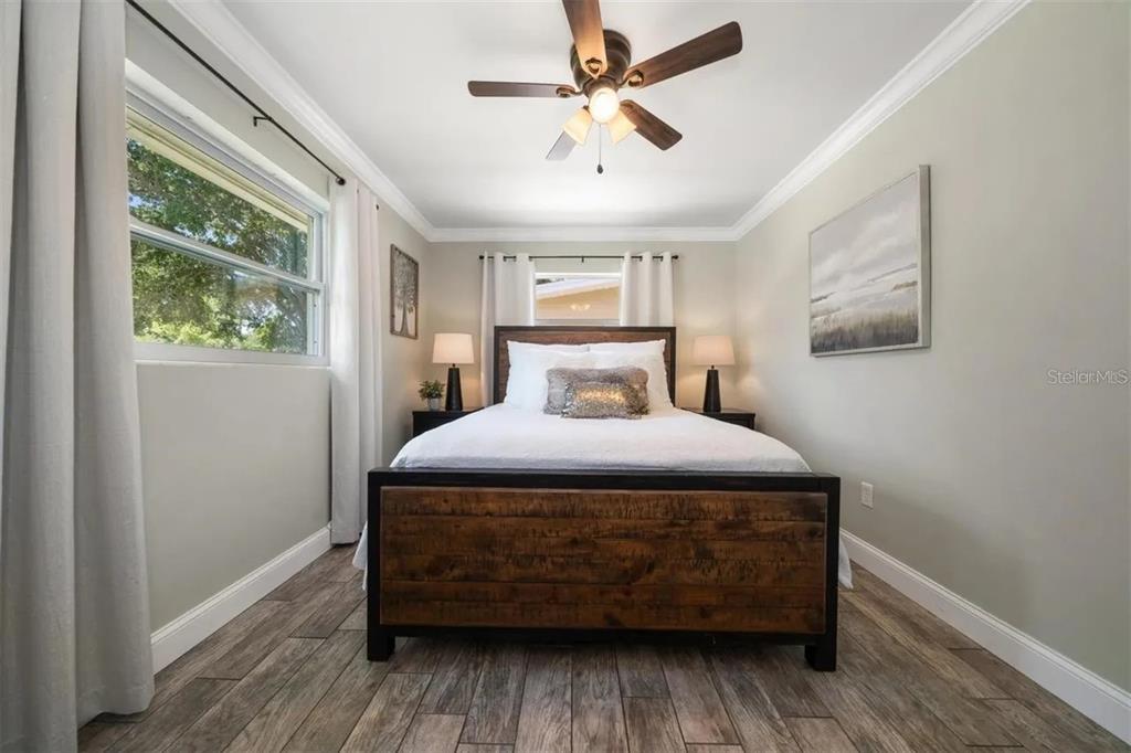 A bedroom features a wooden bed frame, wood-look tile flooring, and a ceiling fan — 2132 ISABELLE STREET, LARGO, FL