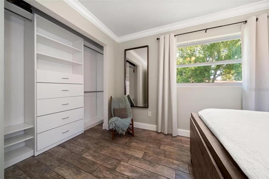 A bedroom with wood-look tile floors, a built-in closet system, and a full-length wall mirror — 2132 ISABELLE STREET, LARGO, FL