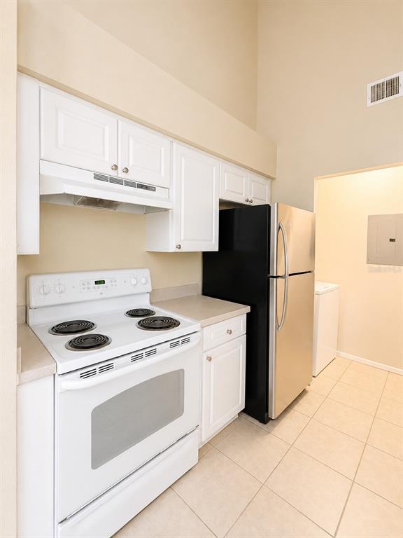 A kitchen features white cabinets, a white electric range, and a stainless steel refrigerator — 1218 BERMUDA LAKES LANE UNIT 201, KISSIMMEE, FL