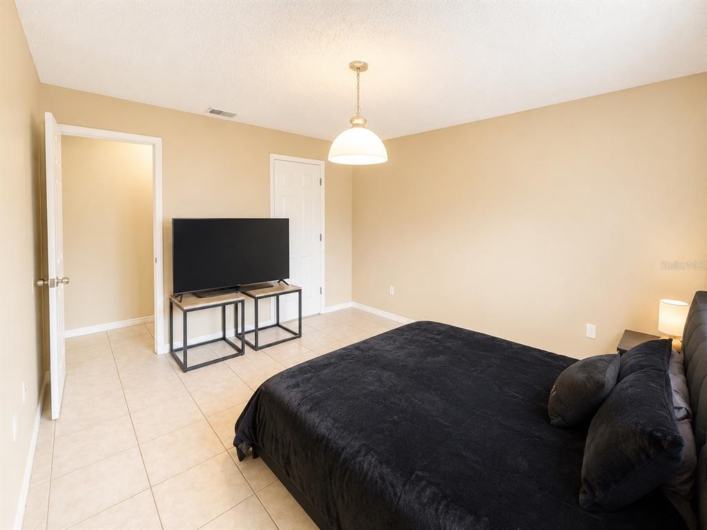 An open-concept kitchen and living area with tile flooring and a sliding glass door — 1218 BERMUDA LAKES LANE UNIT 201, KISSIMMEE, FL
