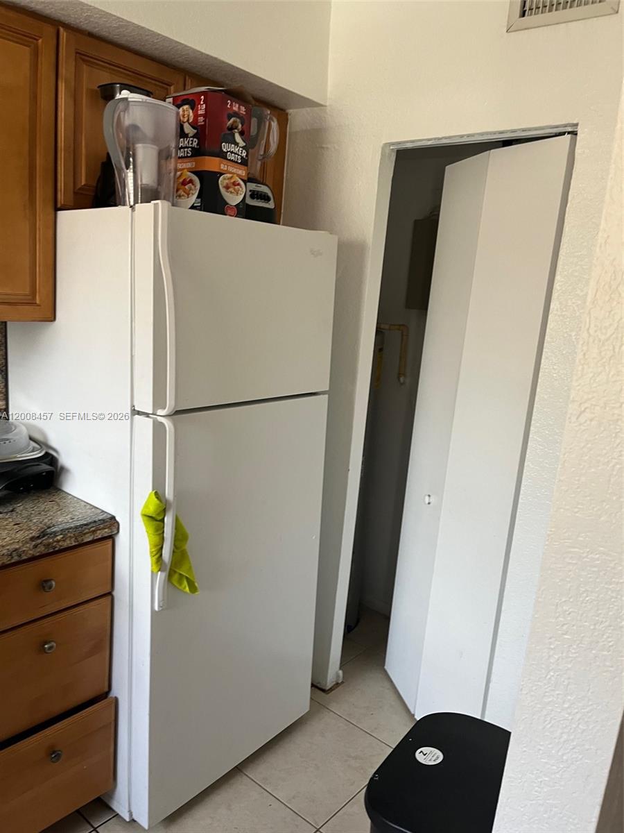 A white refrigerator stands in a kitchen next to a doorway and wooden cabinets — 403 NW 84th St # 403, Miami FL 33150, MIAMI, FL