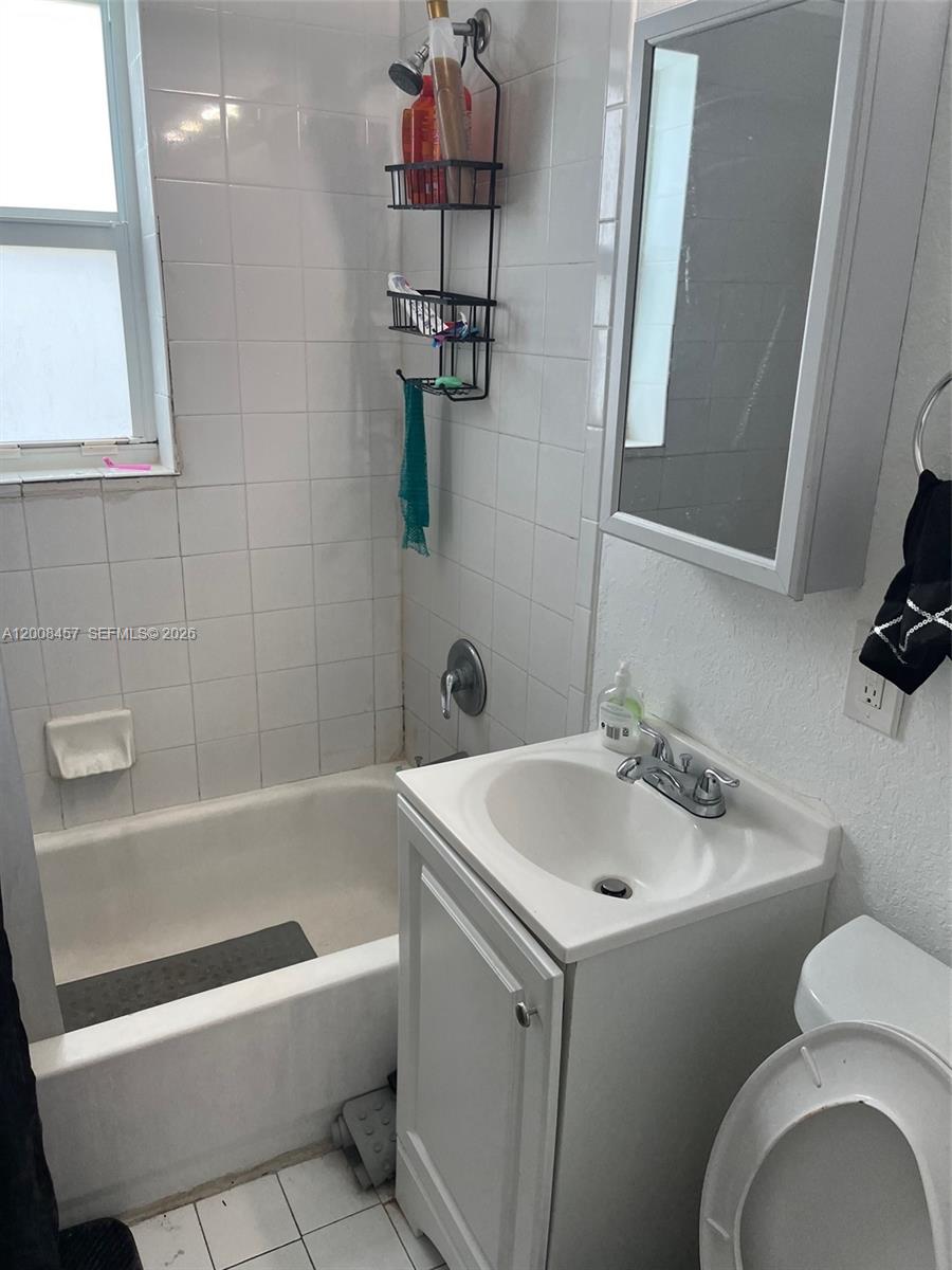 A small bathroom features a white vanity, a toilet, and a tiled shower-tub combination — 403 NW 84th St # 403, Miami FL 33150, MIAMI, FL