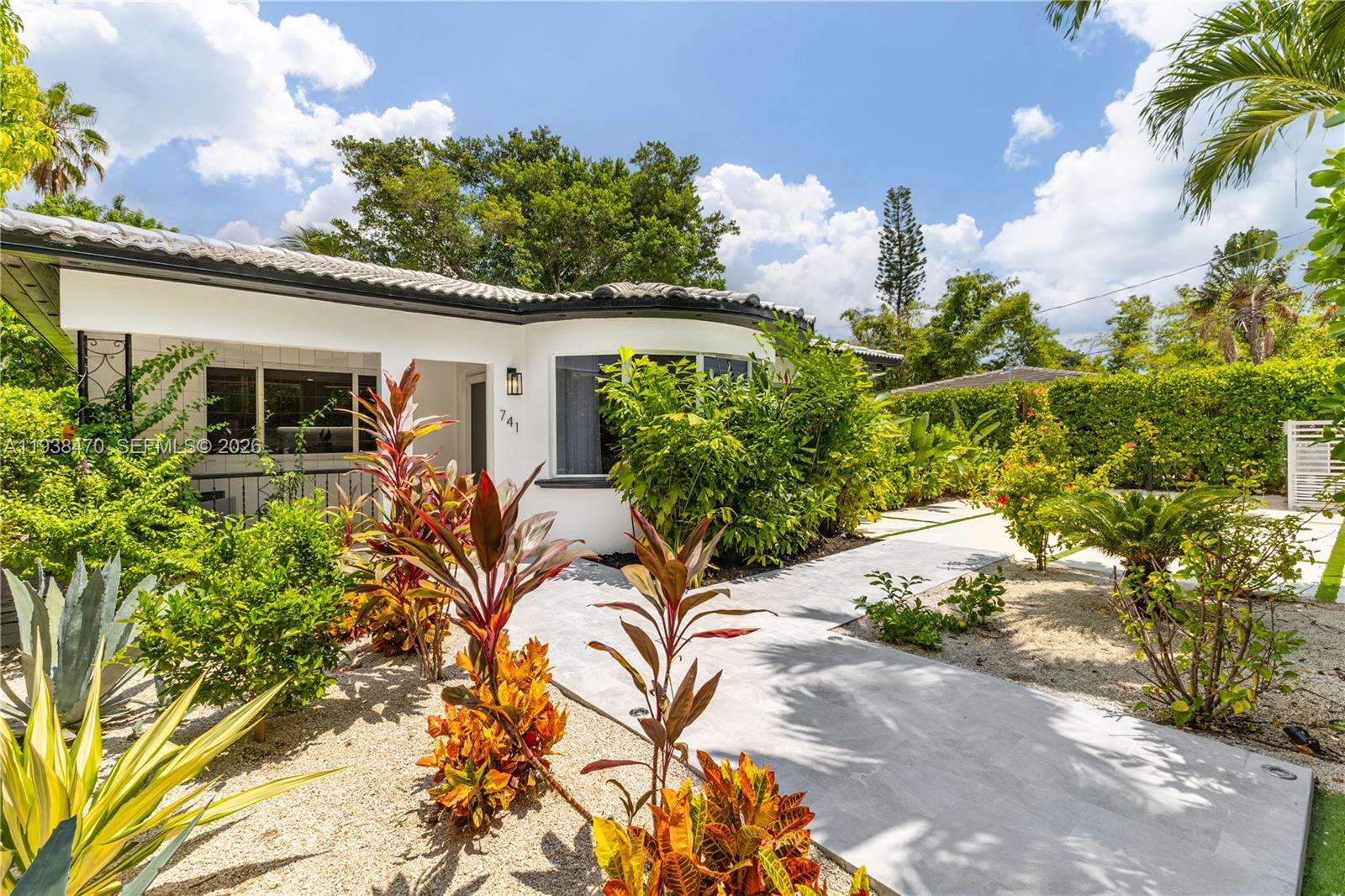 A white house with a curved wall and a concrete walkway surrounded by tropical landscaping — 741 NE 87th St, Miami FL 33138, MIAMI, FL