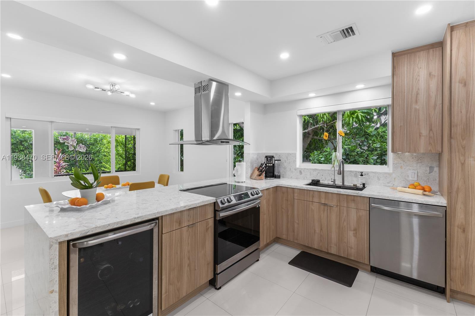 A modern kitchen features light wood cabinets, white quartz countertops, and stainless steel appliances — 741 NE 87th St, Miami FL 33138, MIAMI, FL